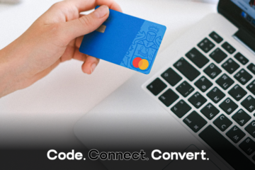 A close-up of a person's hand holding a blue credit card above a laptop keyboard, preparing to make an online payment.