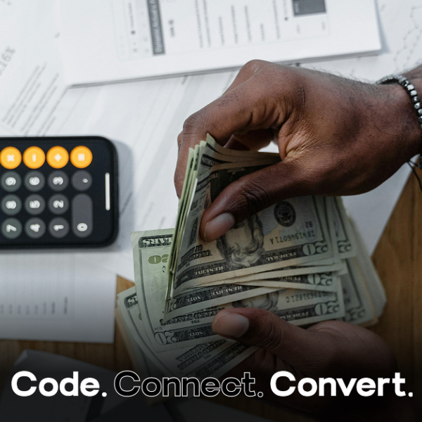 An overhead view of a person's hands counting a fan of US dollar bills over a desk scattered with financial documents and a smartphone showing a calculator.